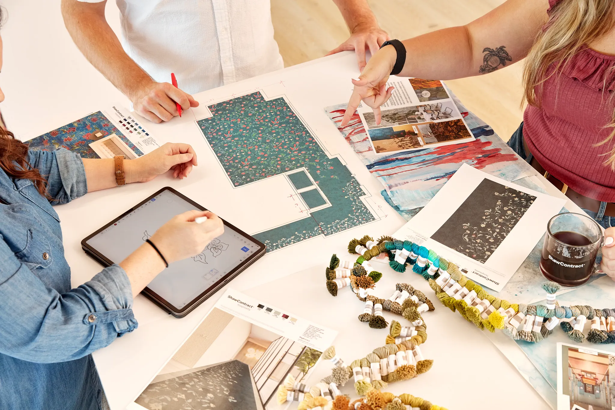 Design team collaborating over flooring samples and blueprints