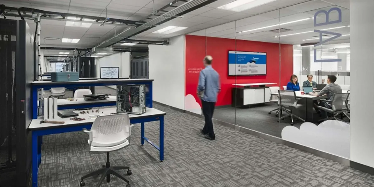 Modern workplace with commercial carpet tile flooring, featuring a collaborative meeting room and workstations