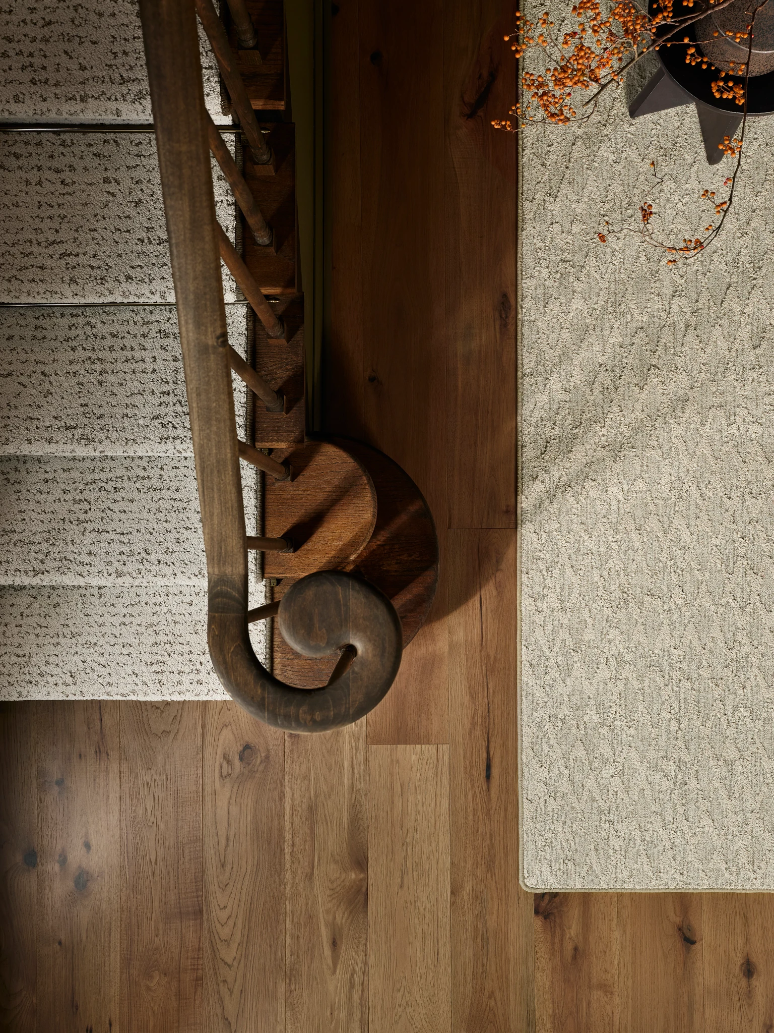 Elegant wooden staircase with detailed balusters and a textured beige carpet runner