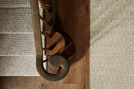 Detailed Wooden Staircase and Foyer with Beige Carpet and Hardwood Flooring Elegant wooden staircase with detailed balusters and a textured beige carpet runner