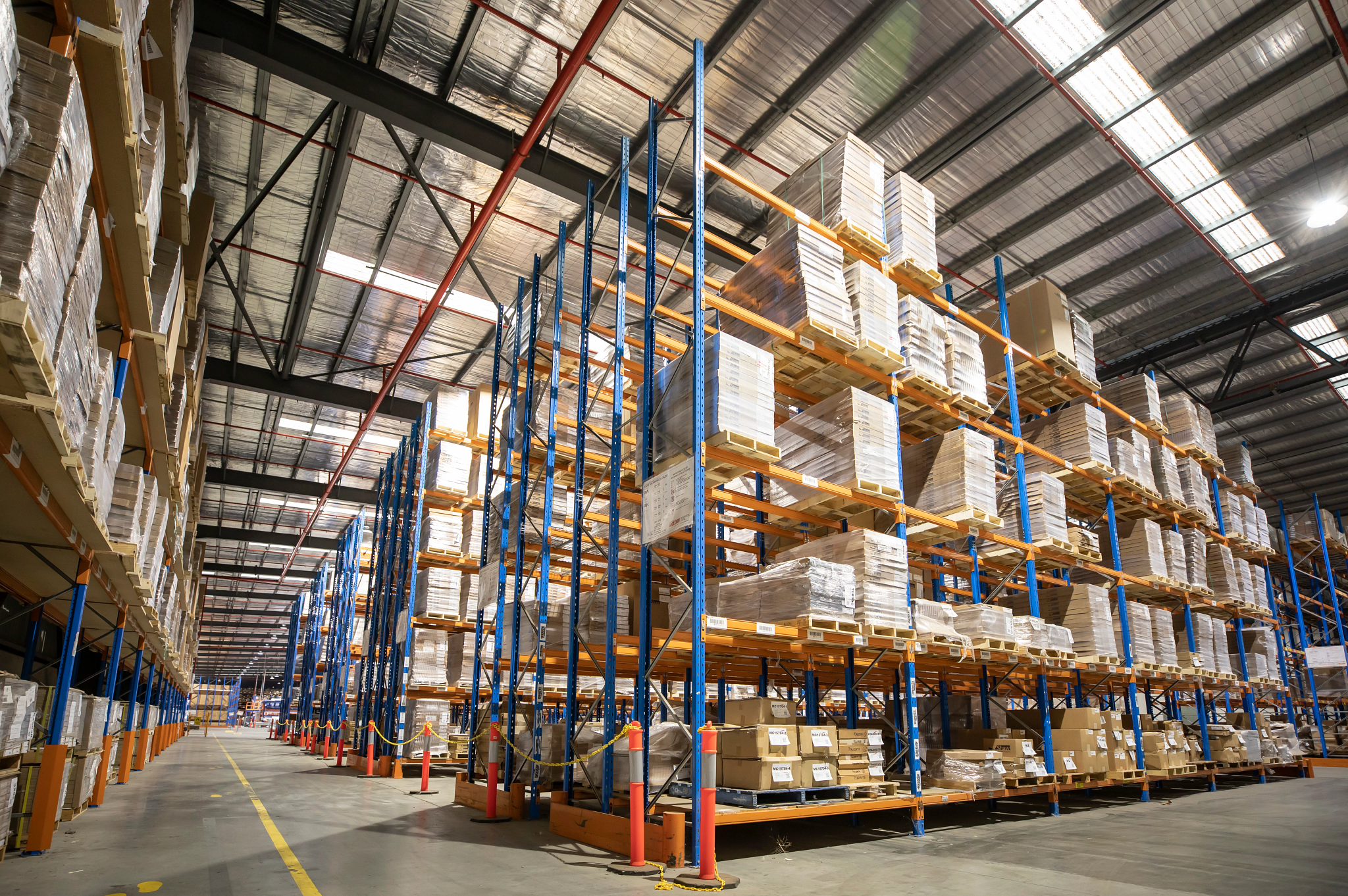 Industrial Warehouse Storage Solutions with High Shelving and Pallets Warehouse interior with high shelves stacked with boxes and pallets, showcasing industrial storage solutions