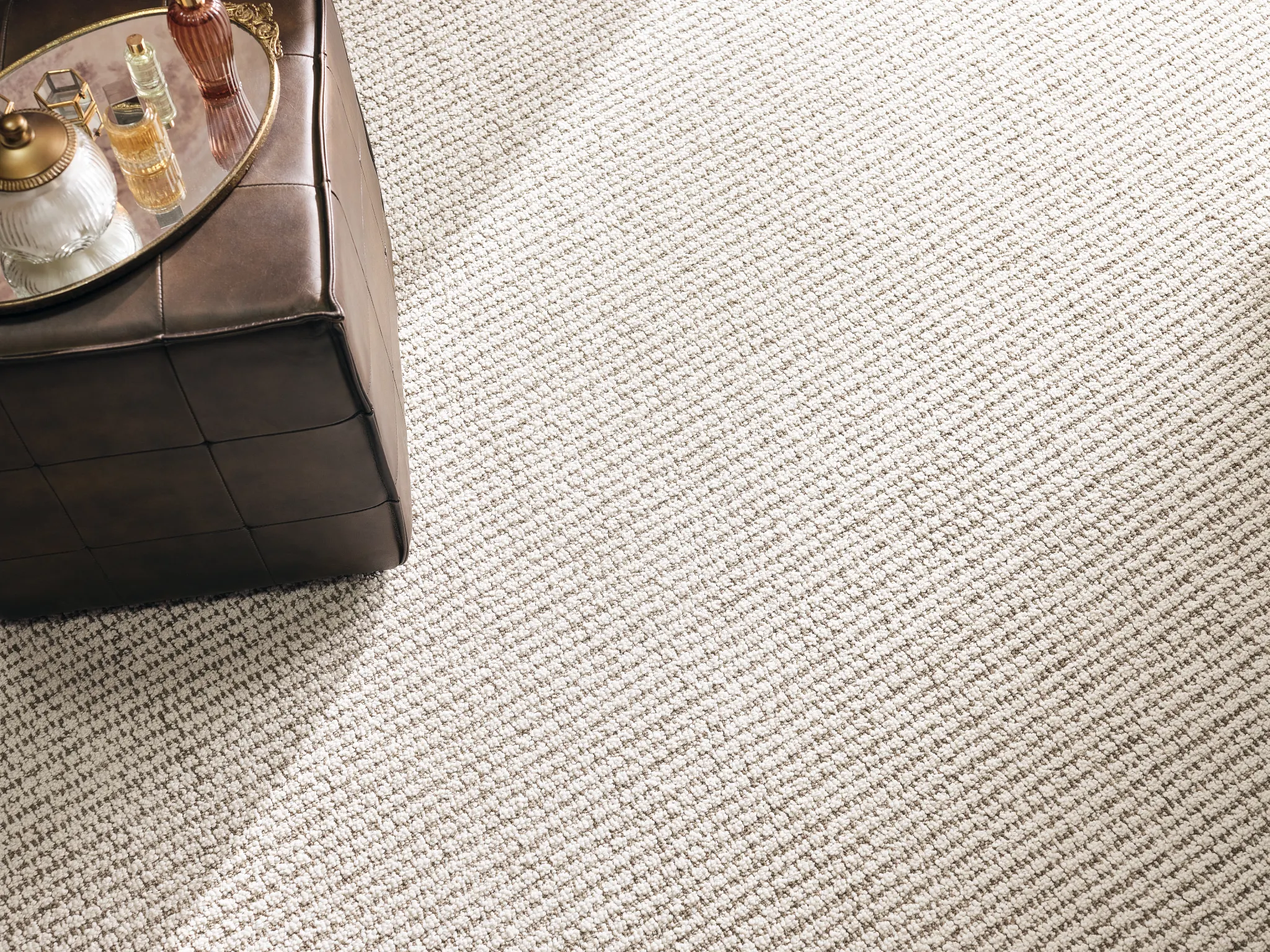 Beige synthetic carpet with textured pattern and leather ottoman