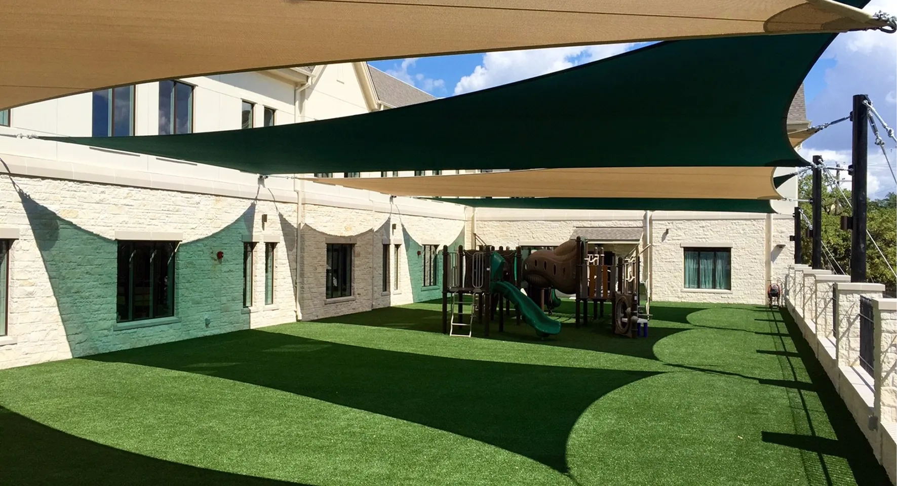 Outdoor playground with artificial grass and shade sails