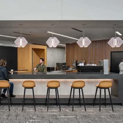 Contemporary Workplace Lounge with Commercial Carpet Tile Flooring Modern workplace lounge area with commercial carpet tile flooring, featuring a bar counter with stools and pendant lighting