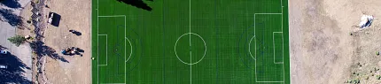 Soccer field with artificial grass surrounded by nature Aerial view of a soccer field with artificial turf surrounded by trees and dirt paths