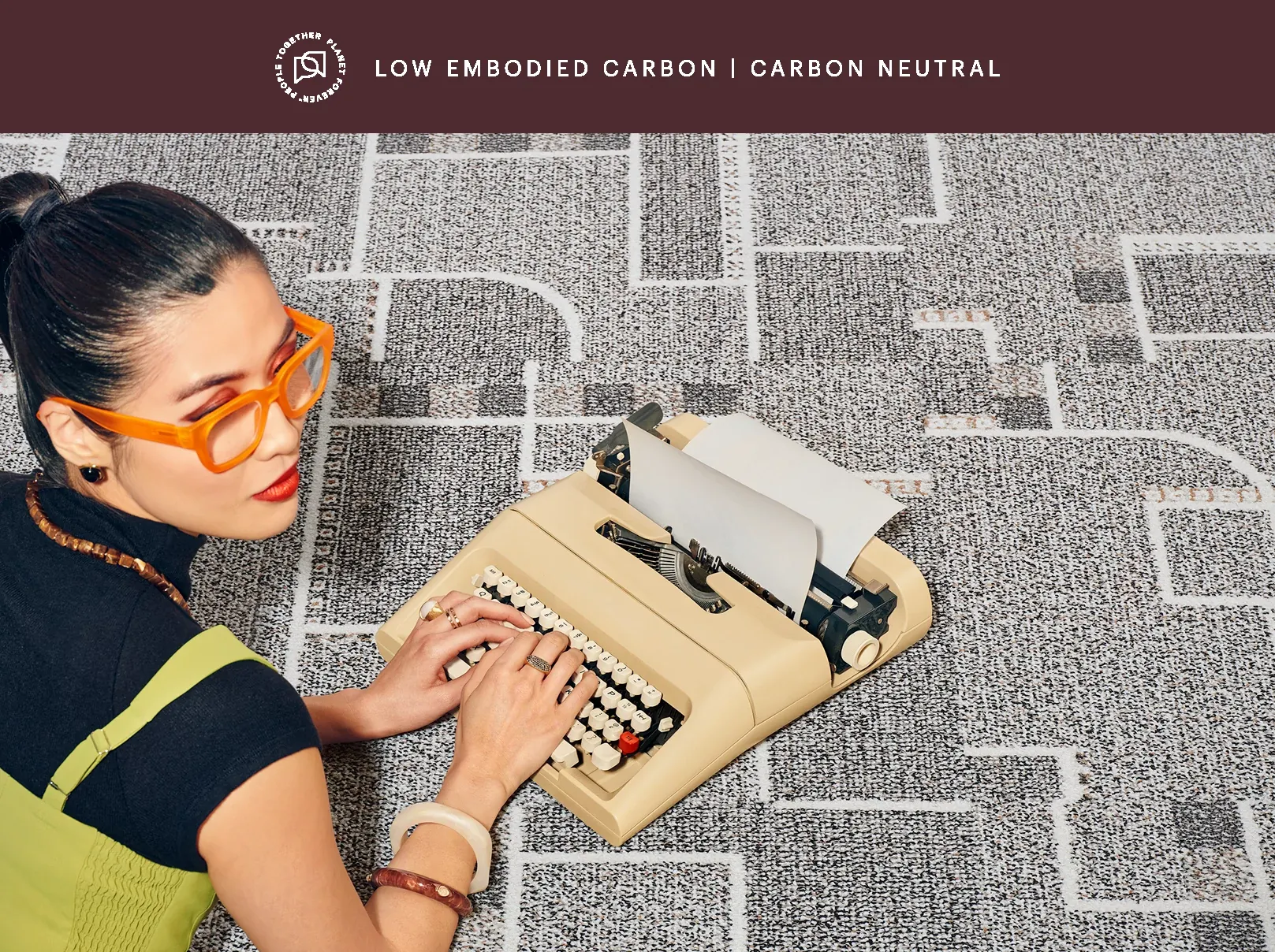 Woman typing on a typewriter on patterned carpet