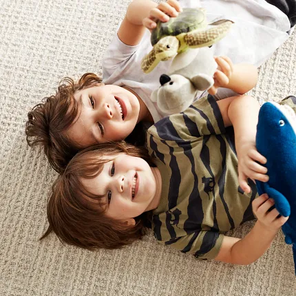 Beige Broadloom Carpet - 12 ft Width Children playing on beige broadloom carpet with plush toys